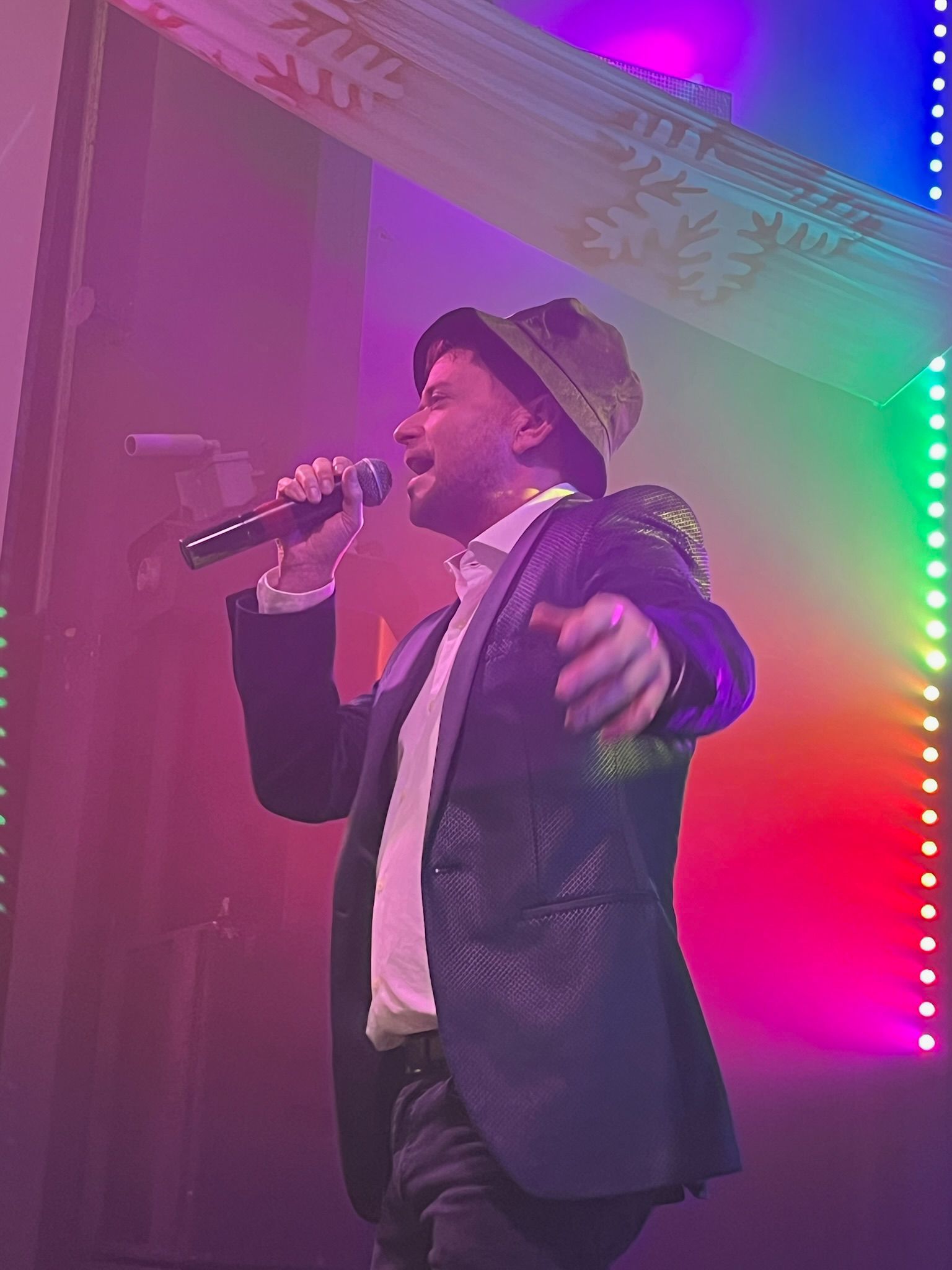 Ilan singing under colourful stage lights